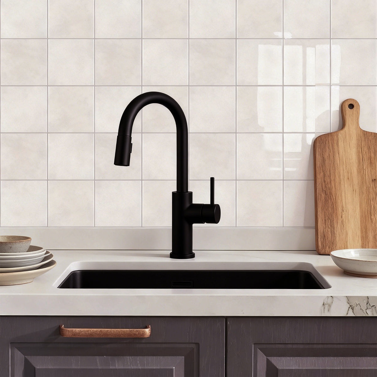 Modern kitchen sink with black faucet against a tiled wall.
