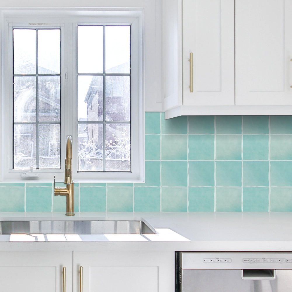 Modern kitchen with white cabinets, a window, and a teal backsplash.