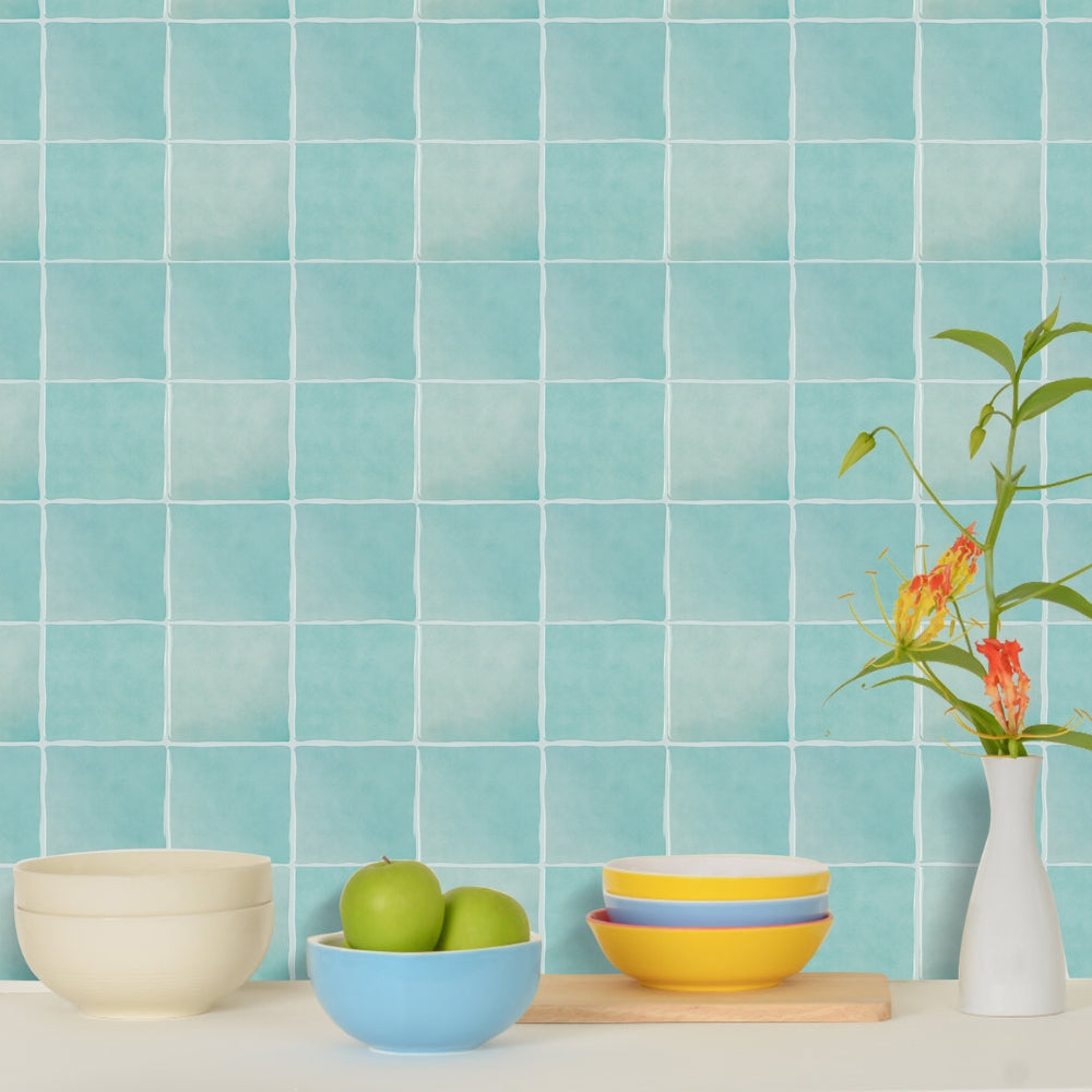Kitchen counter with bowls, apples, and a vase against a blue tiled wall.
