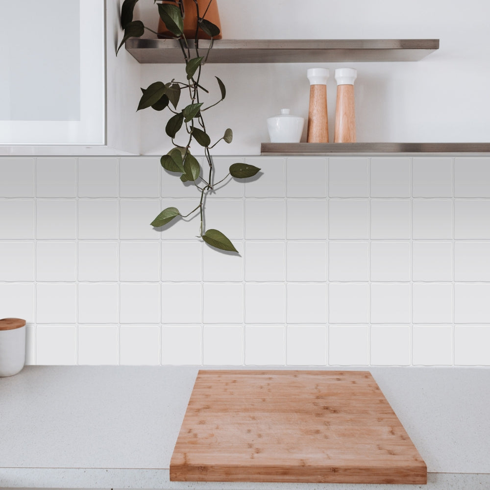 Wooden cutting board on a kitchen counter with white tiled wall and shelves in the background.