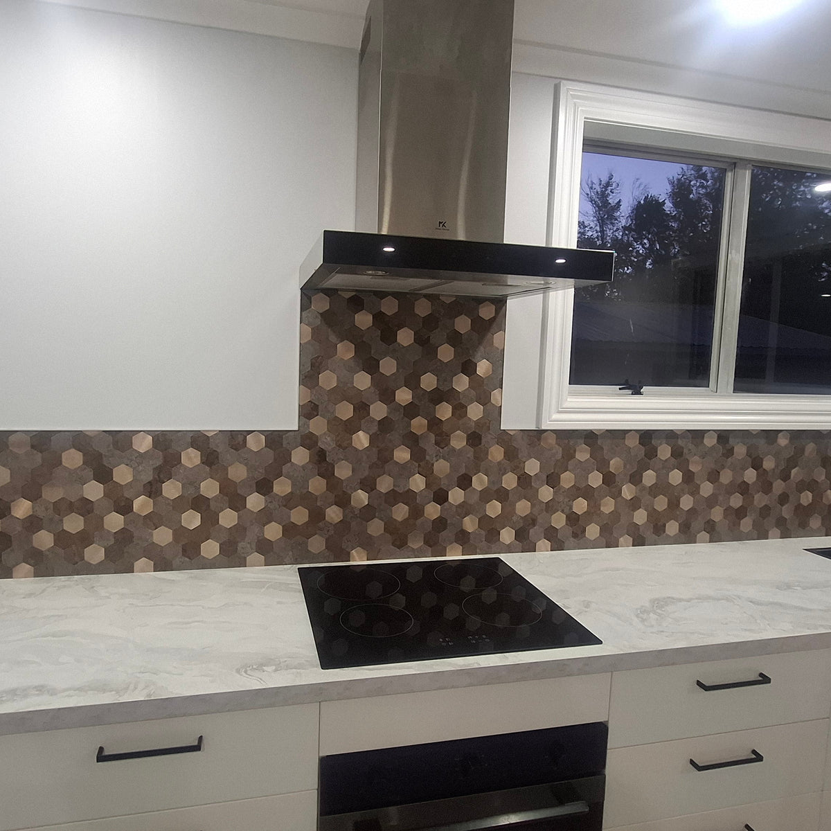 Modern kitchen with white cabinets, marble countertop, and patterned backsplash.