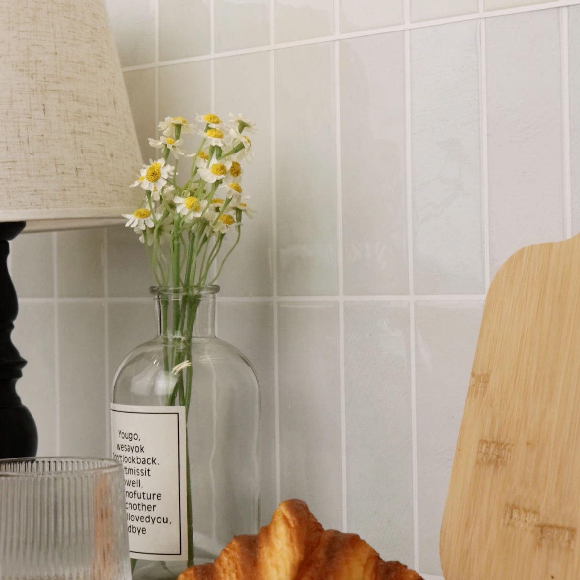 Baked croissant on a kitchen counter with a vase of flowers and a wooden cutting board.