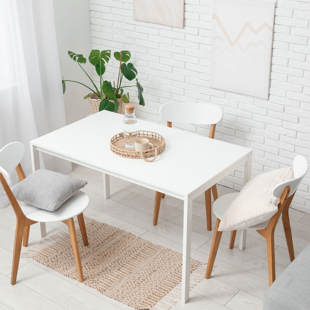 Dining area with a white table and chairs against a white brick wall.