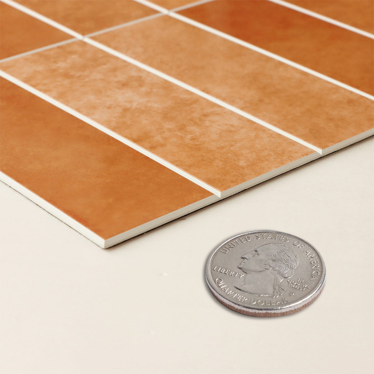 A sheet of orange stacked subway tiles in profile next to an American coin
