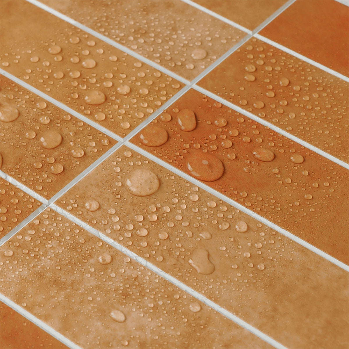 Close-up of square terracotta-colored tiles with white grout lines, covered in water droplets.