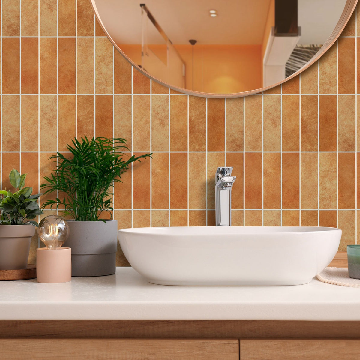 Burnt orange matte stacked subway tile splashback behind a vanity with a round mirror