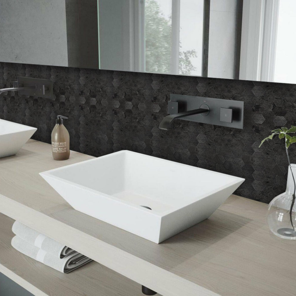 Modern bathroom with a white sink, charcoal hexagon wall, and decorative elements.