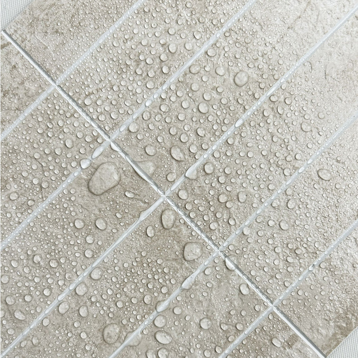stacked beige textured subway tiles with water drops on